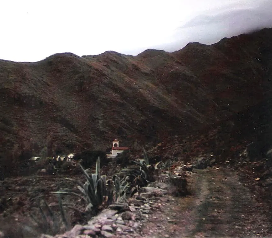 El camino de tierra que entra a la quebrada hacia 1940, con el campanario de la capilla asomando abajo entre los cerros.