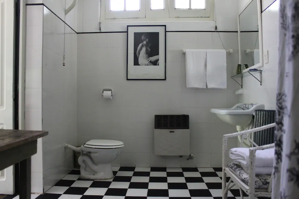 Un baño antiguo con piso ajedrezado blanco y negro.