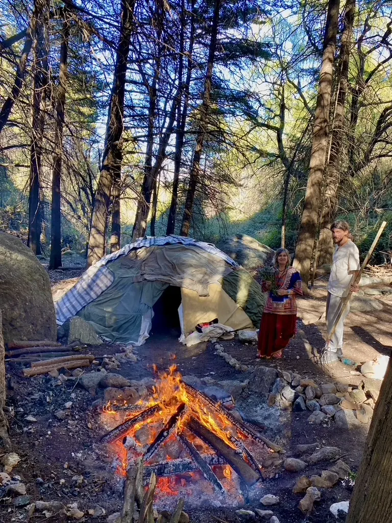 Una carpa de temazcal junto al fogón encendido, en el bosque.