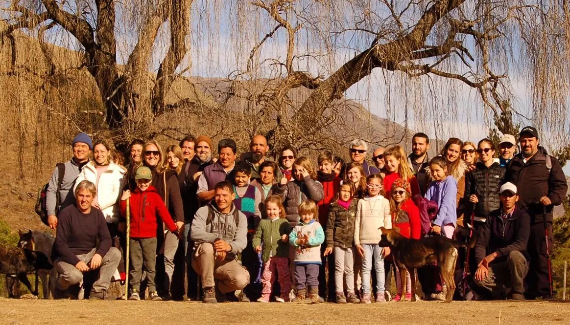 Foto de grupo numeroso en invierno, con los álamos pelados y la sierra detrás.