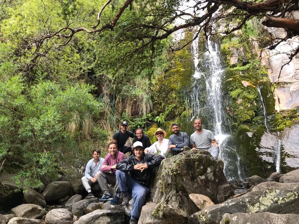 Un grupo posando sobre las rocas al pie de la cascada.