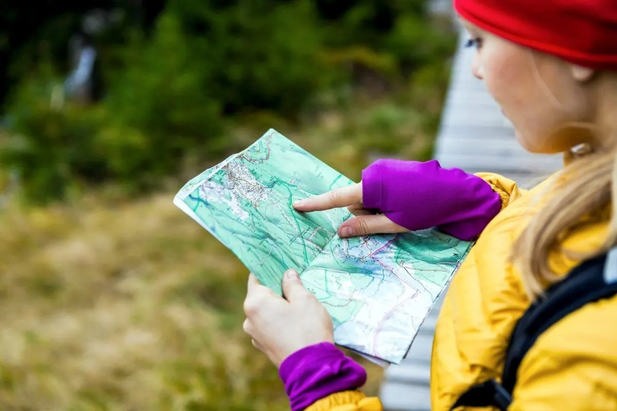 Una persona de campera amarilla leyendo un mapa topográfico en el sendero.
