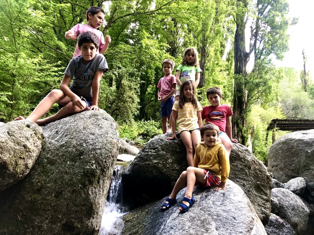 Chicos sentados en las rocas grandes del arroyo.