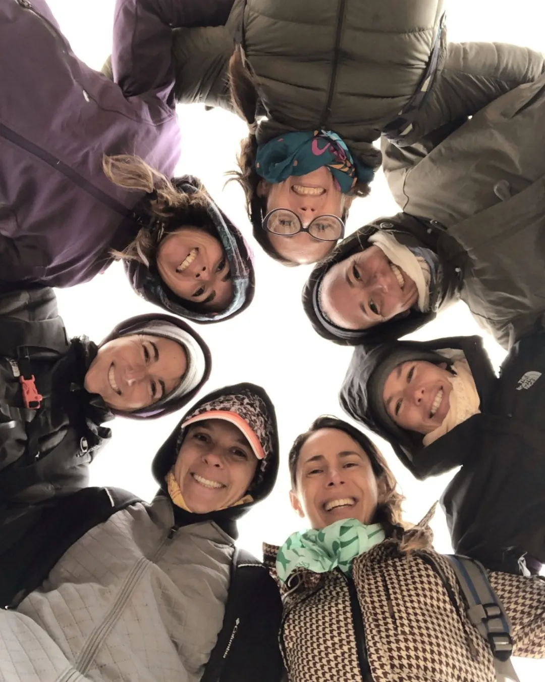 Una ronda de mujeres vista desde abajo, las cabezas formando un círculo.