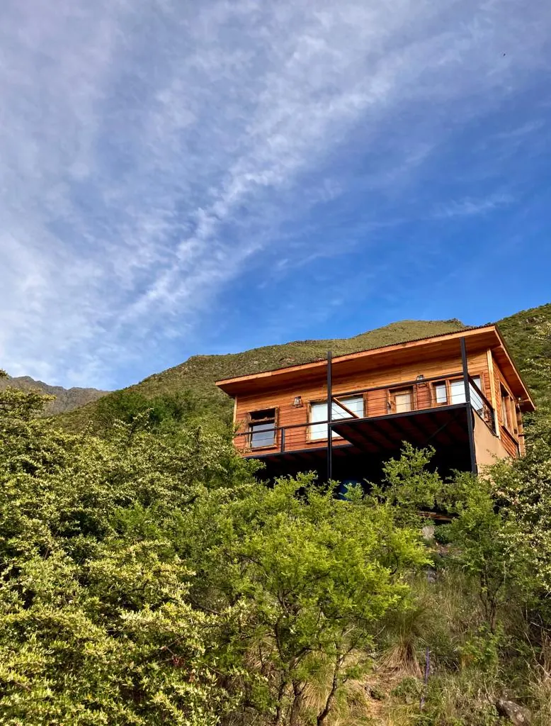Una suite de madera levantada sobre la ladera, contra el cielo.