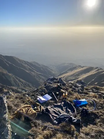 Las cosas de pasar la noche tiradas sobre el pasto del filo de la sierra, con el valle abajo al amanecer.
