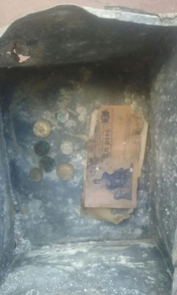 El interior de la caja de plomo con billetes y monedas de la época.