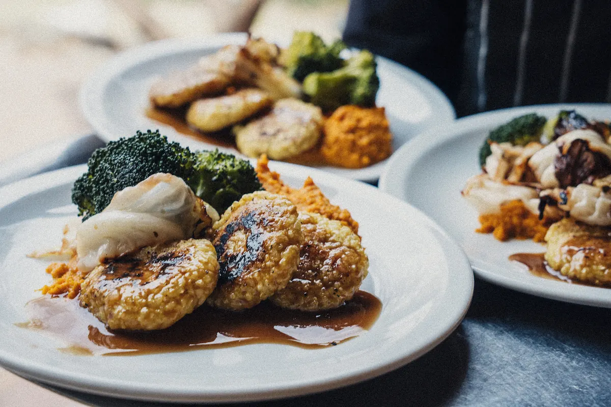 Tres platos de milanesas de quinoa con brócoli, coliflor asado y puré de calabaza, en la mesada de la cocina.