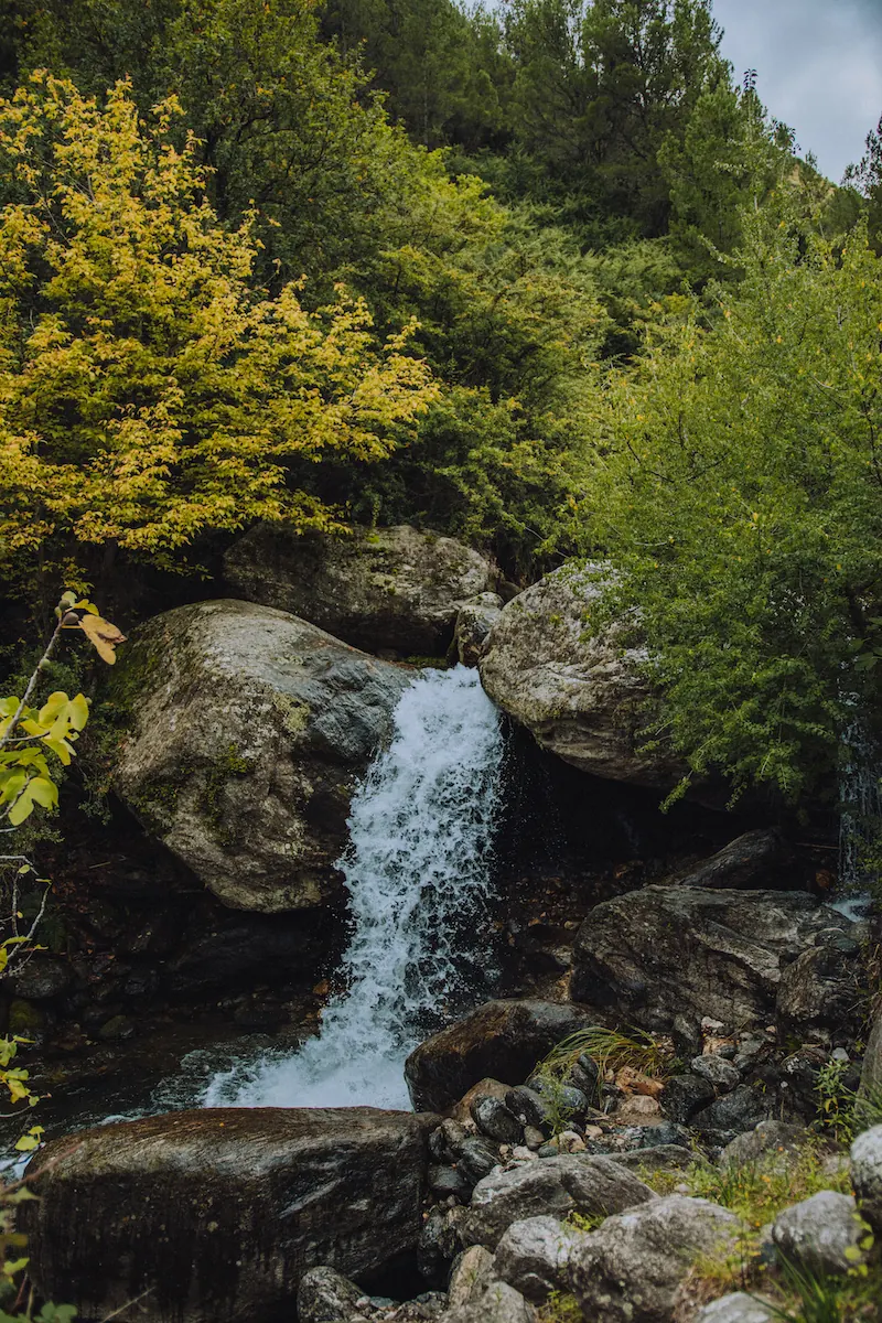 Un salto de agua cayendo entre las rocas del arroyo.