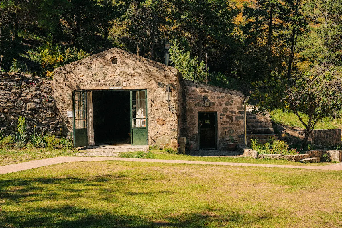 El galpon de piedra con el porton verde.
