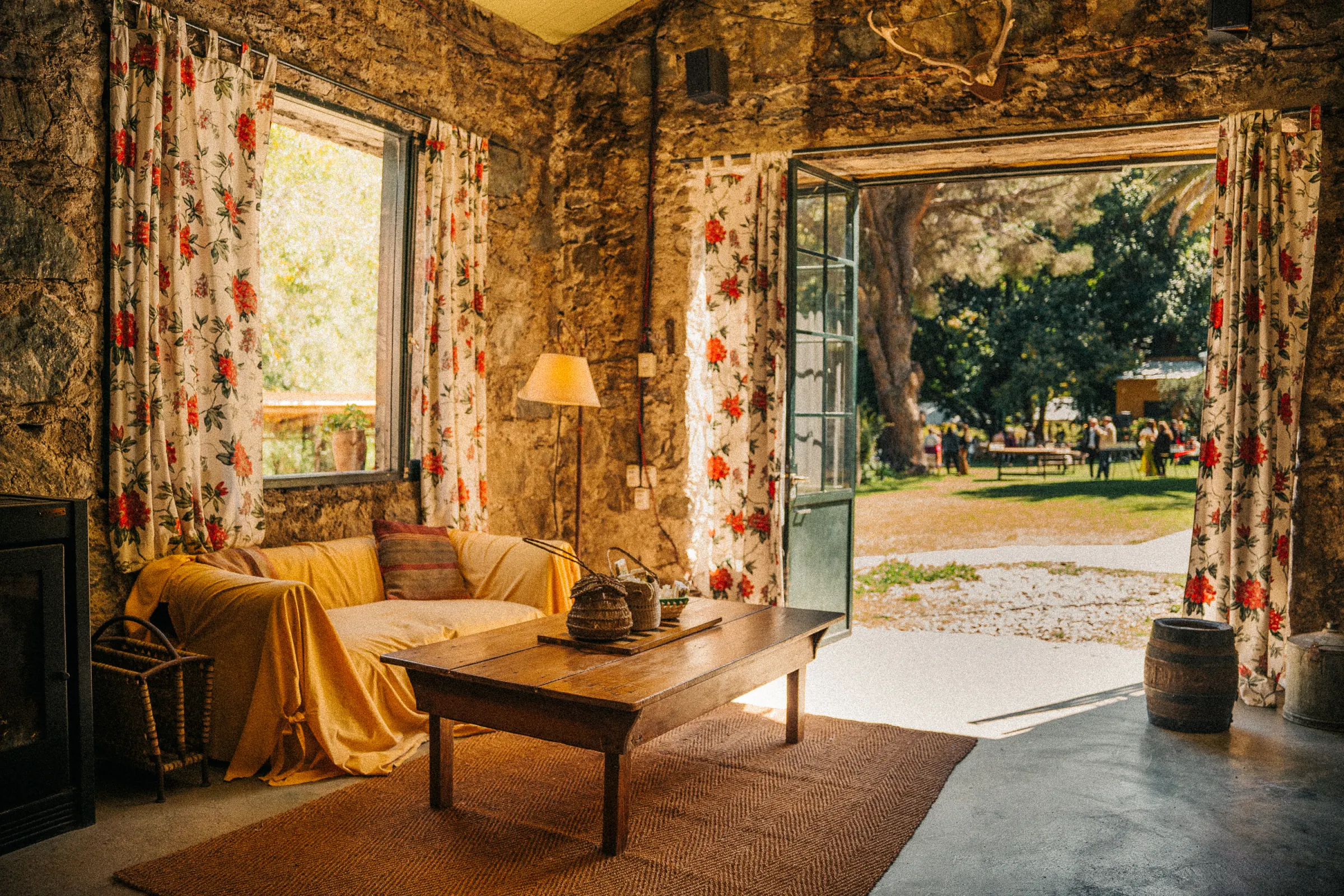 Living con sillon amarillo, cortinas floreadas y la puerta abierta al parque.