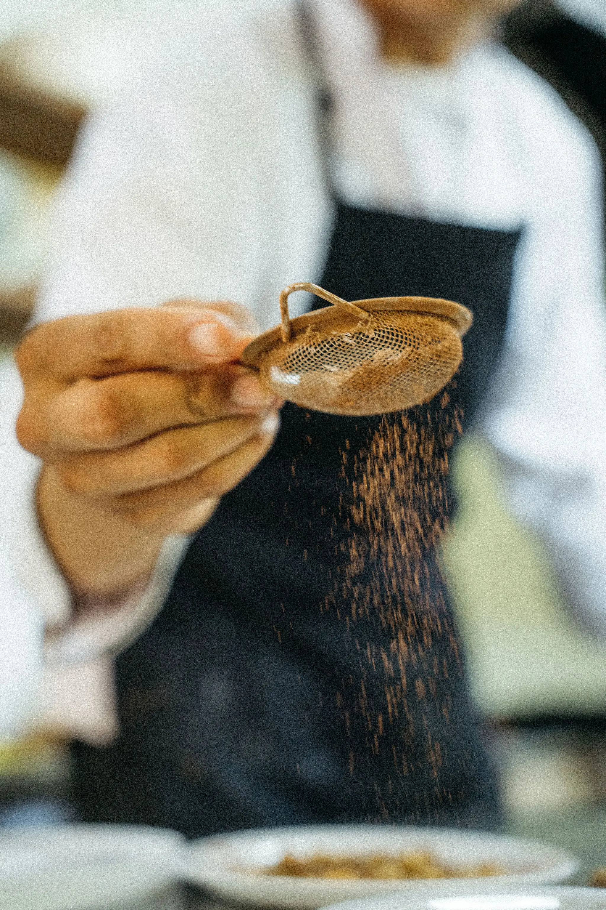 Un cocinero tamizando cacao sobre un plato.