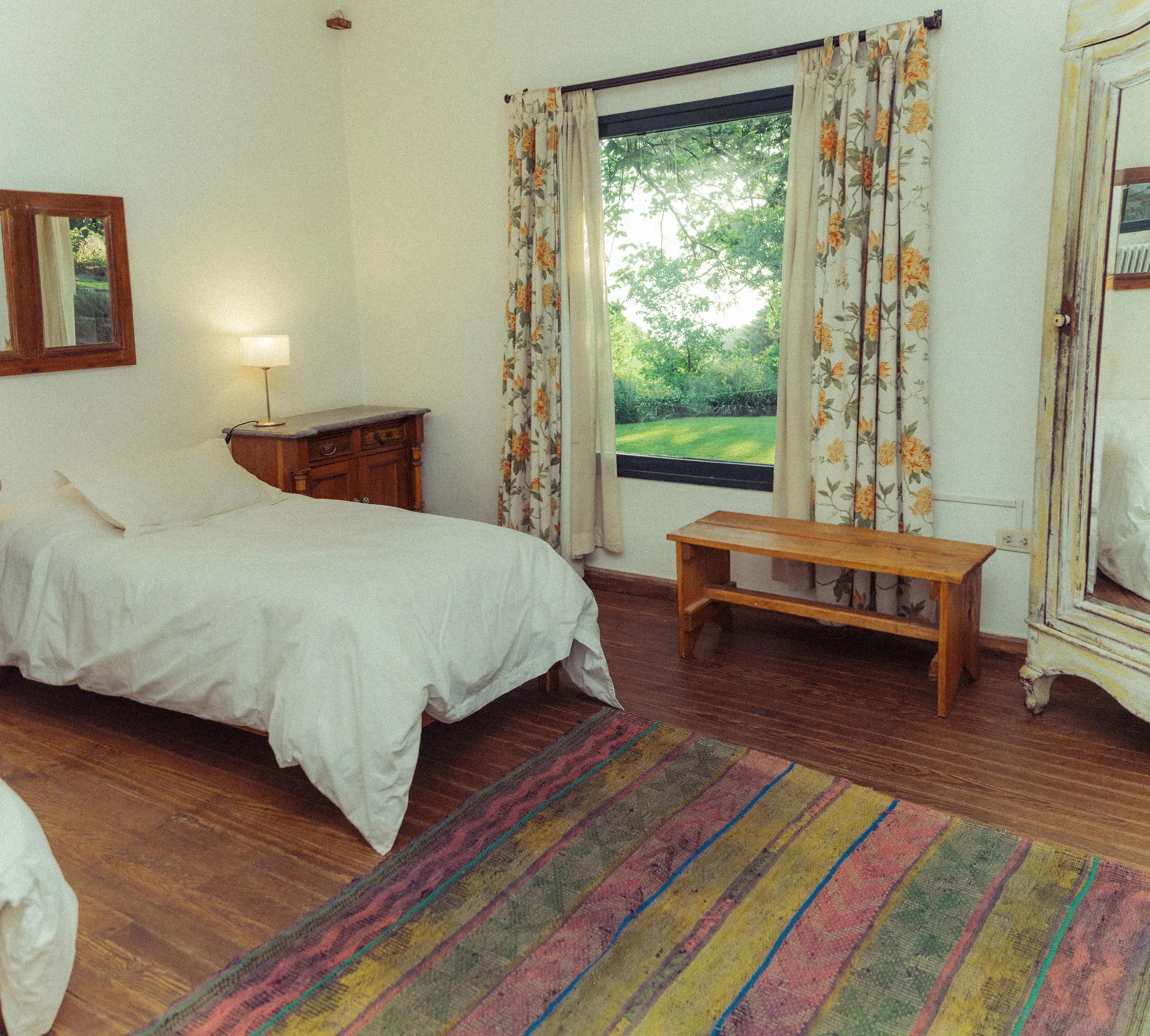 Dormitorio con alfombra de rayas y ventana al parque.