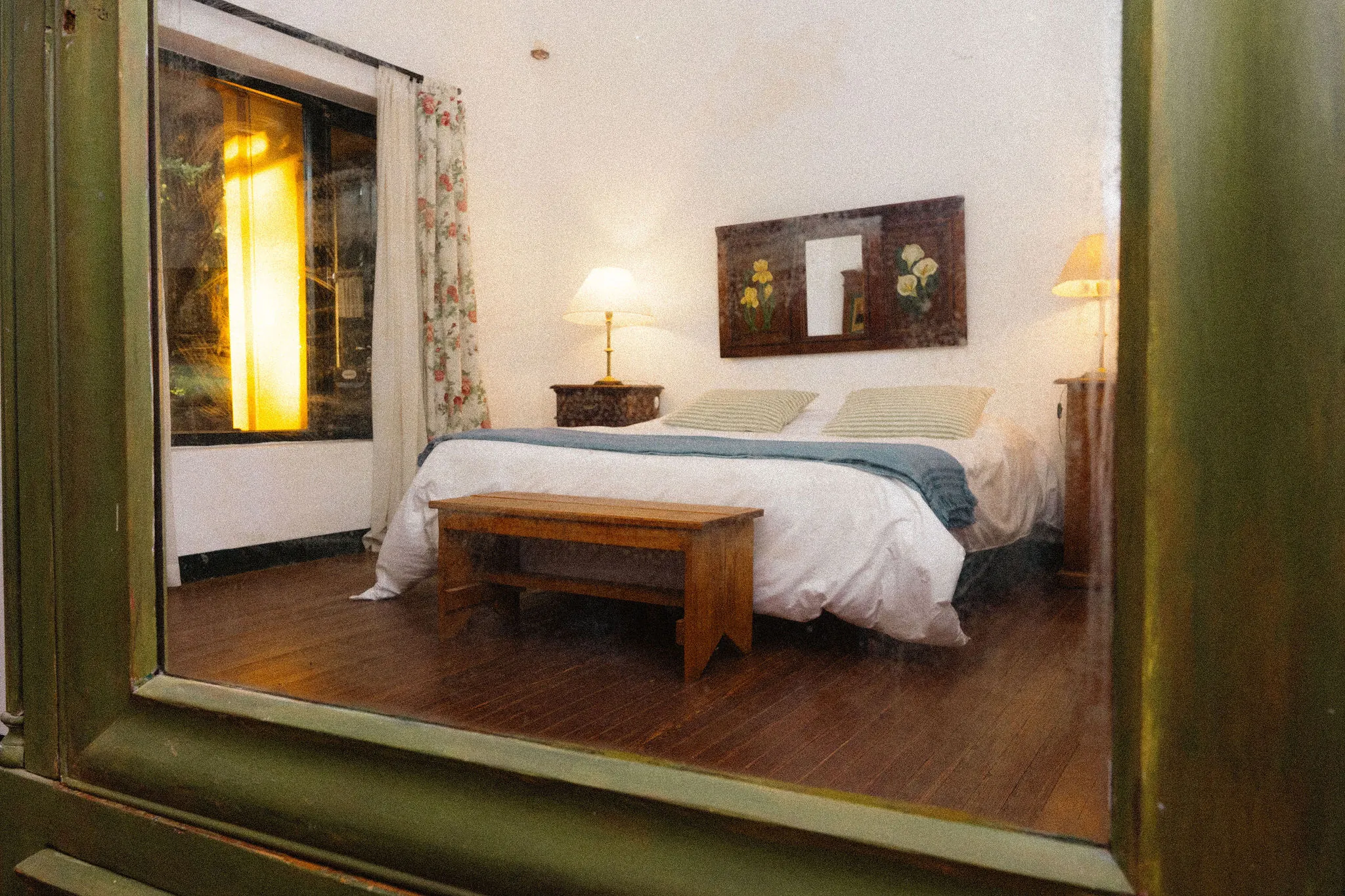 Dormitorio visto desde el marco de una ventana verde.