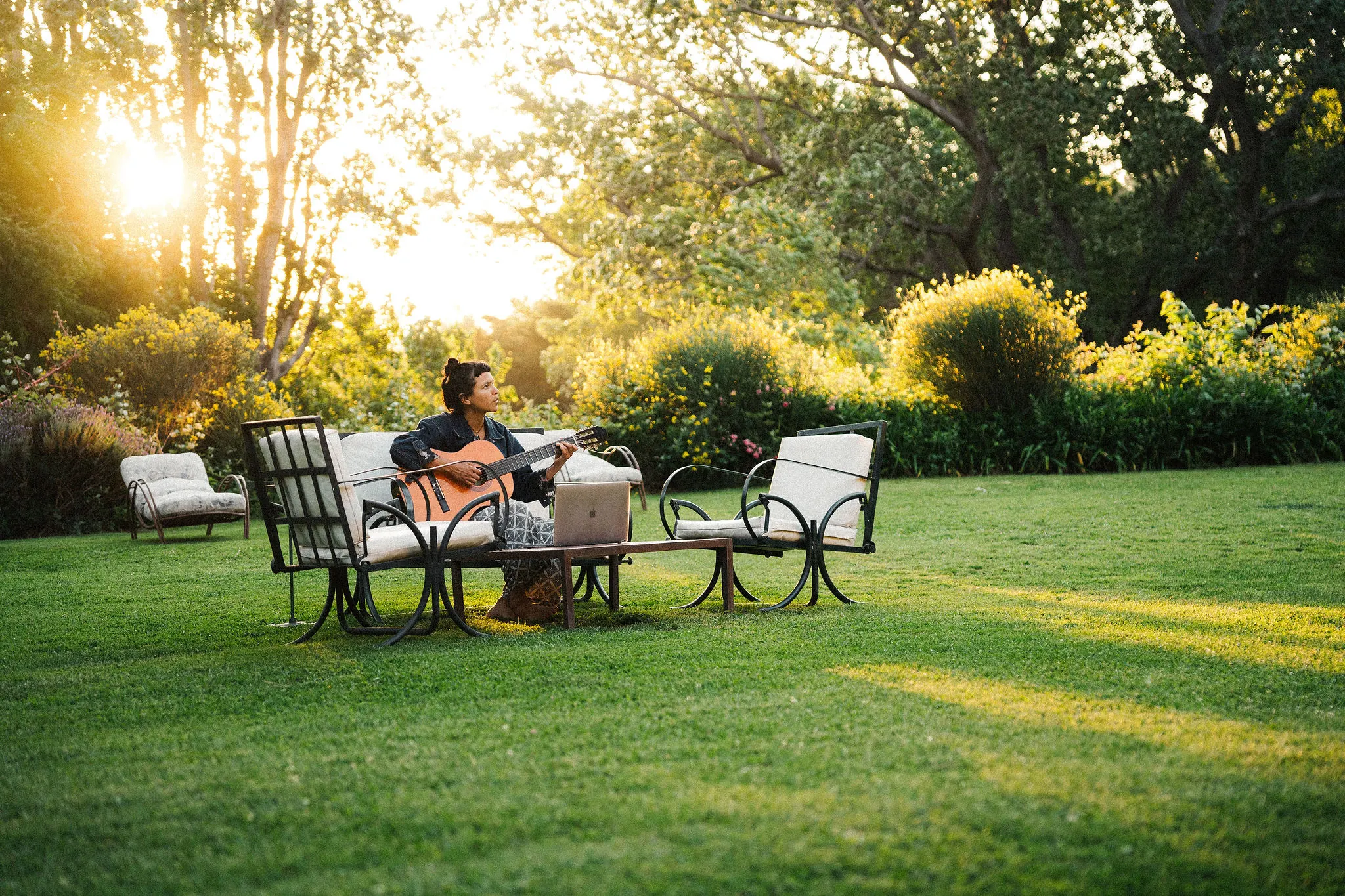 Alguien tomando mate sentado en el parque, al atardecer.