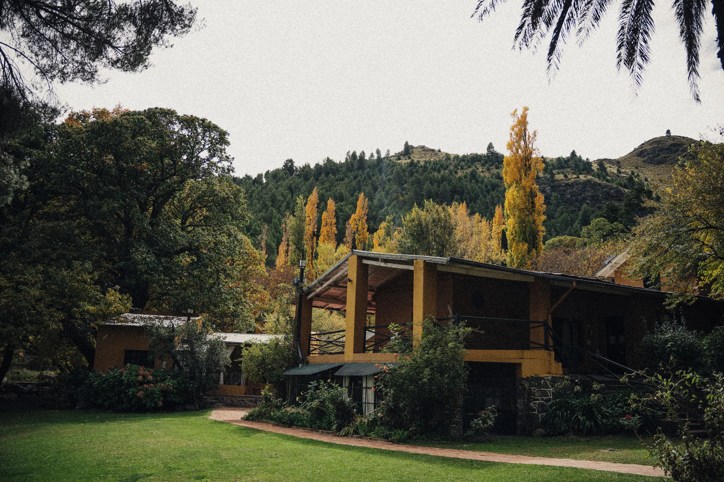 La casa con su galeria, los alamos en otono y la sierra detras.