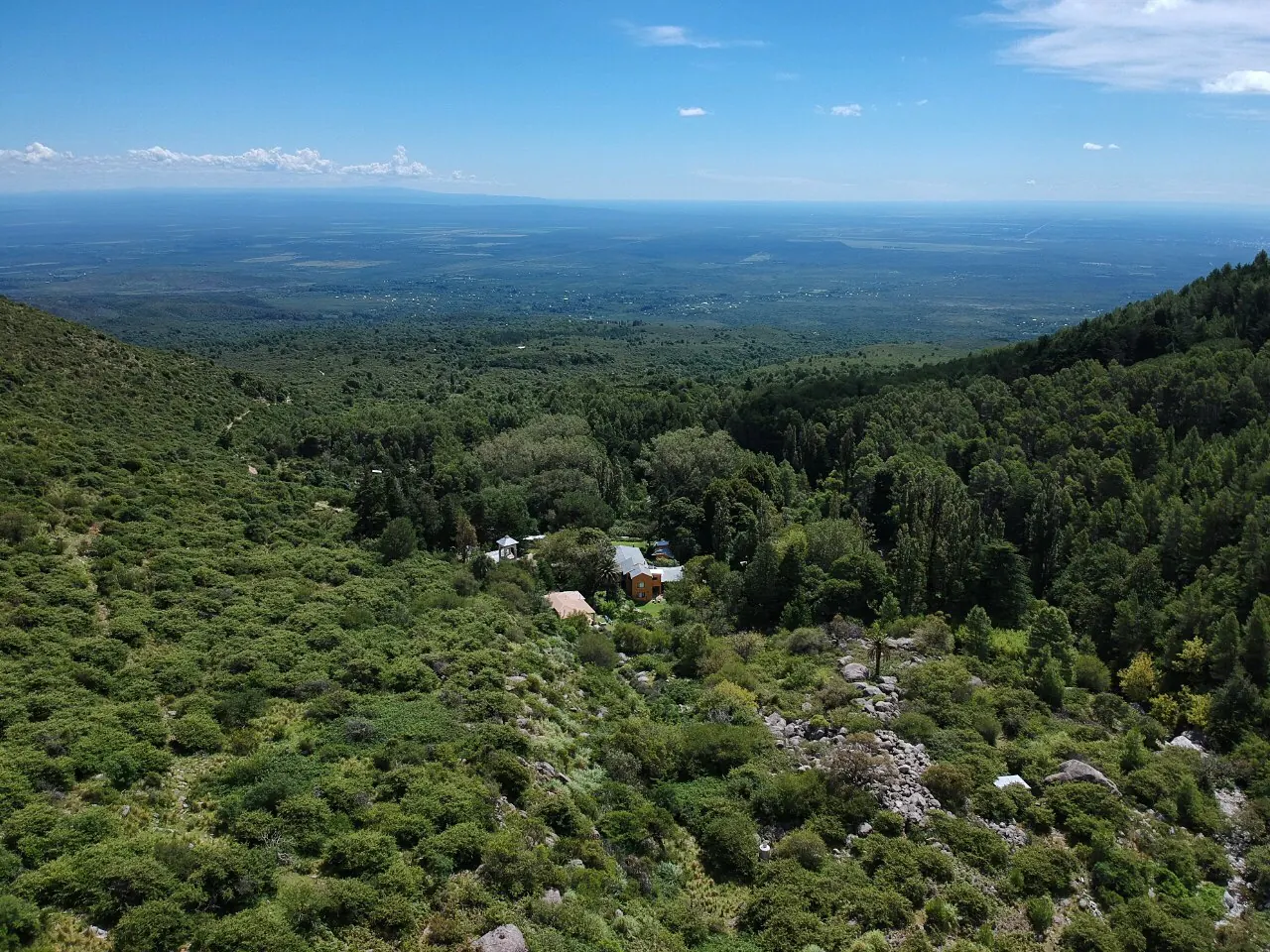 Vista aérea de la casa en el fondo de la quebrada, con el llano de Traslasierra al fondo.