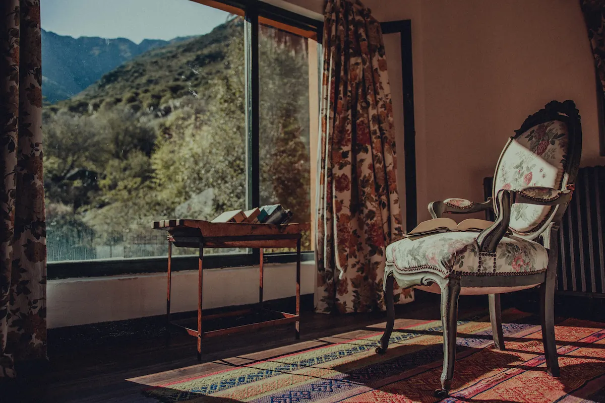 Habitación con ventanal a la sierra, sillones y alfombra sobre piso de madera.