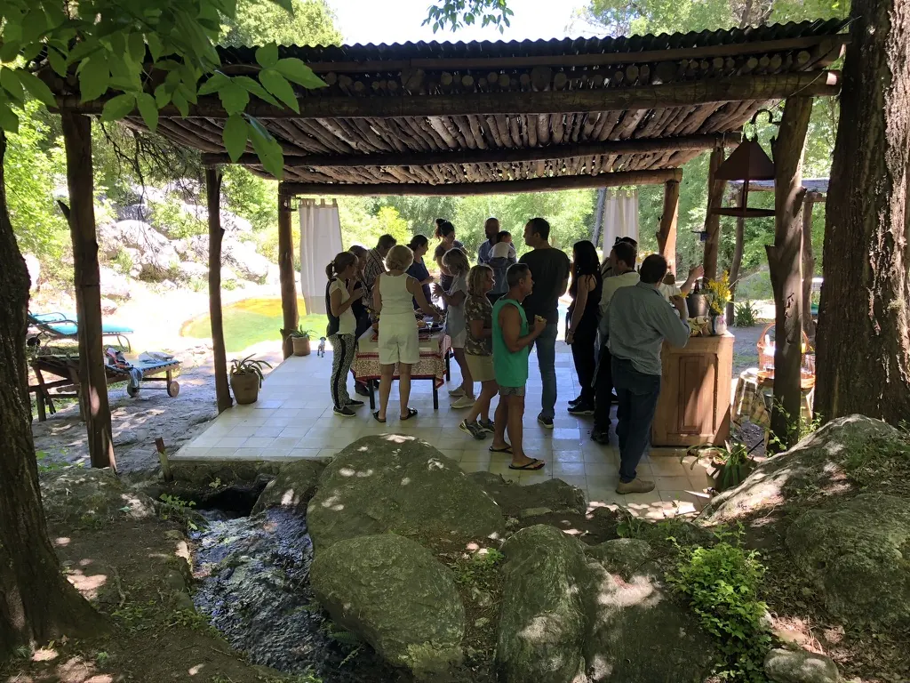 Gente reunida bajo la pérgola junto al arroyo.