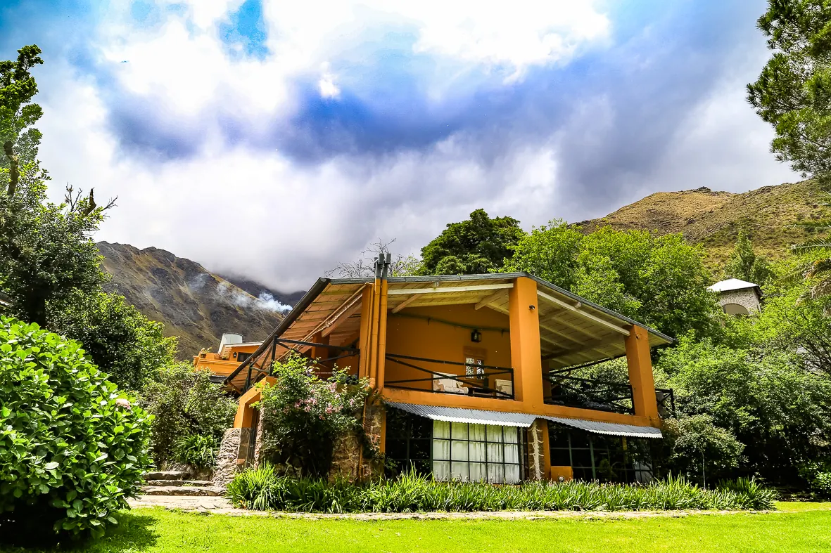 La galería de columnas de la casa ocre, con las sierras y las nubes detrás.