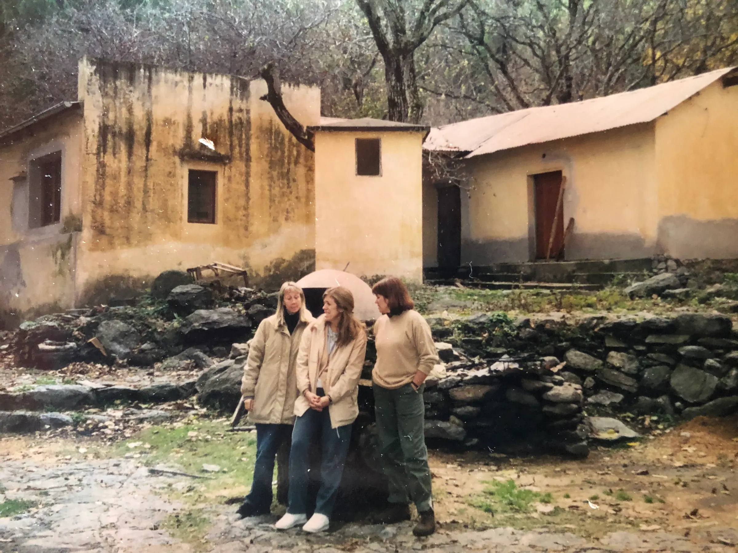 Tres personas paradas frente a las construcciones de la quebrada todavía descascaradas, antes de la restauración.