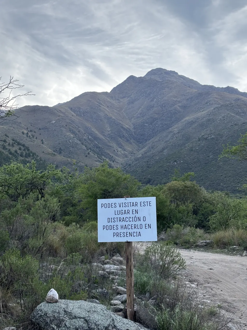 Cartel sobre el camino con el Cerro lindero de fondo.