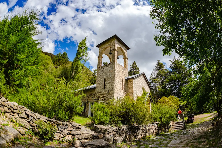 La capilla de piedra con su campanario y el camino de piedra que llega a la puerta.