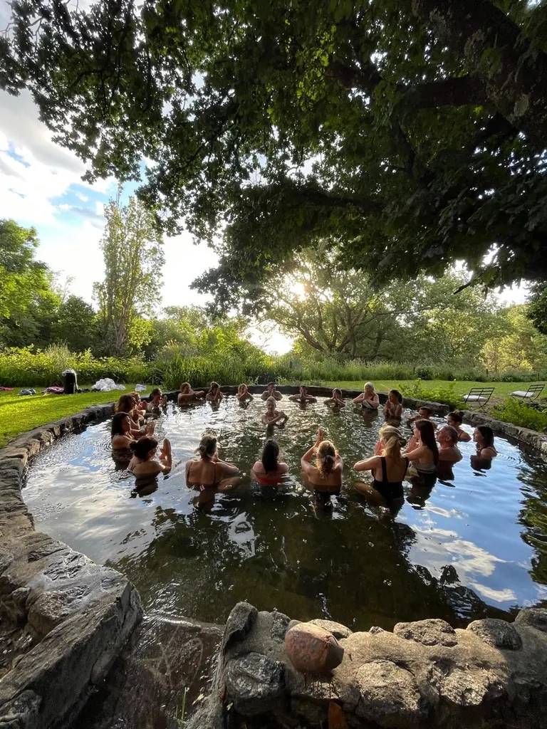 Un grupo adentro del estanque de piedra, en ronda y con el agua a la cintura, bajo el roble grande.
