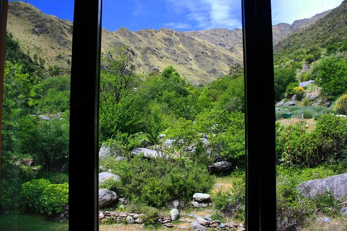 La vista desde el ventanal: el verde de la quebrada y el filo de la sierra enfrente.