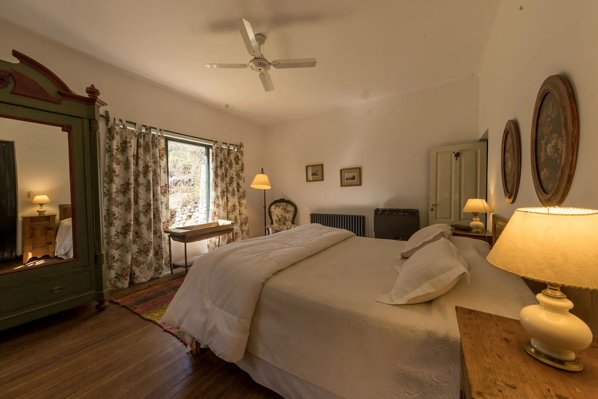 Habitación amplia con cama grande, ropero verde y lámparas encendidas.