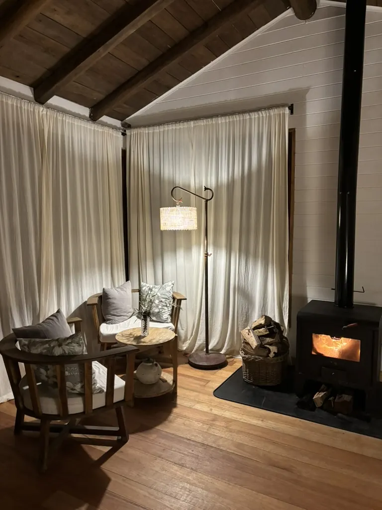 El rincón de estar con la salamandra encendida, dos sillones y una mesa baja de madera.