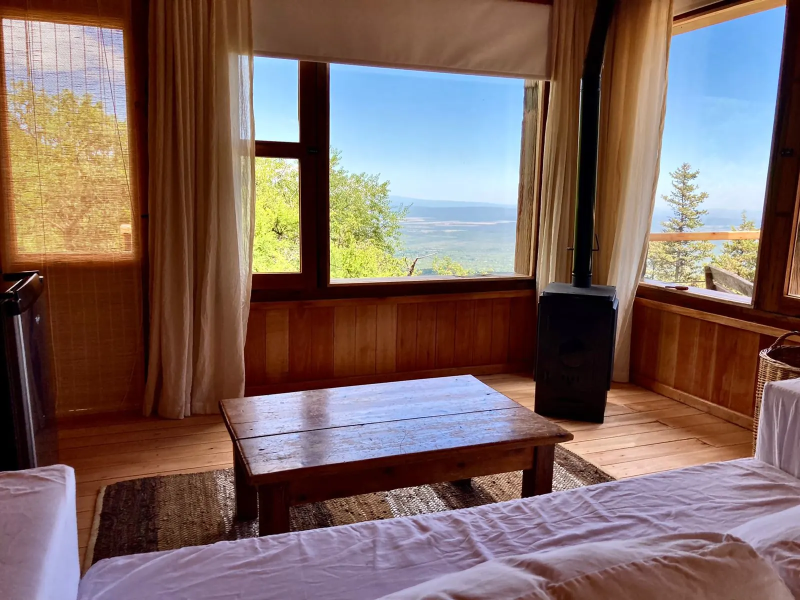 La sala de estar de la suite, con la salamandra, la mesa baja y los ventanales al valle.