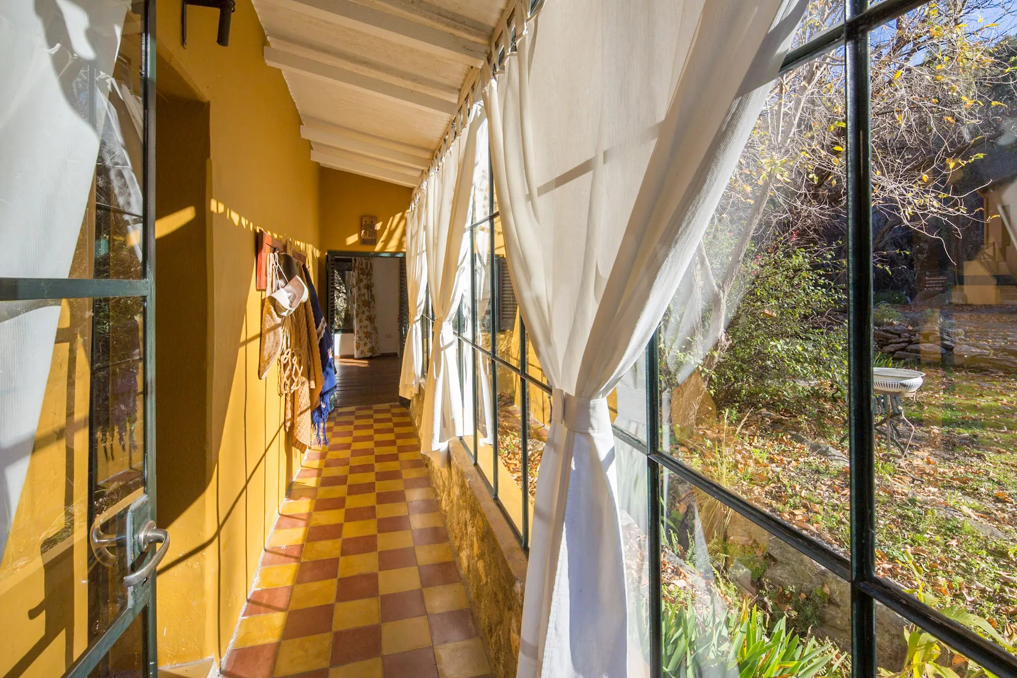 La galería vidriada de piso ajedrezado que corre por fuera de la habitación.