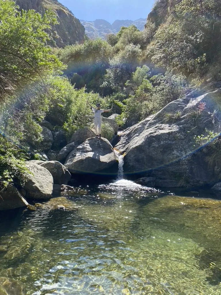 Un salto de agua cayendo a un pozón de agua clara, entre las paredes de roca de la quebrada.